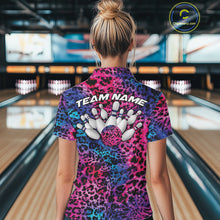Load image into Gallery viewer, Back view of a woman standing at a bowling alley, wearing a purple, blue, and black leopard-print bowling polo with “Team Name” and bowling pins on the back.