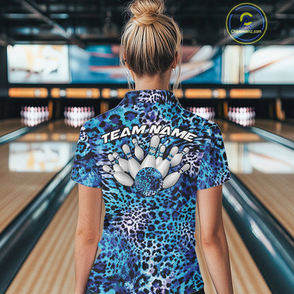 Back view of a woman standing at a bowling alley, wearing a blue, teal, and black leopard-print bowling polo with “Team Name” and bowling pins on the back.
