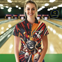 Load image into Gallery viewer, Front view of a female model wearing a black, red, and orange bowling polo shirt featuring a crowned cartoon bowling ball with a royal scepter leading animated bowling pins through vibrant bursts of color in a bowling lane.