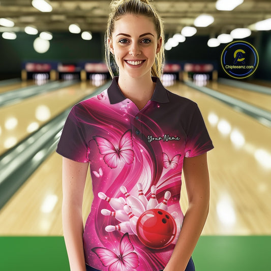 Female model in a bowling center wearing a pink bowling polo decorated with bowling action artwork and butterflies.