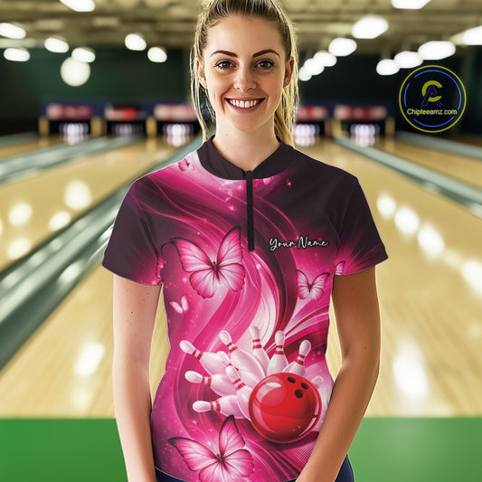 Female model wearing a pink bowling quarter-zip inside a bowling venue with bowling strike and butterfly artwork.