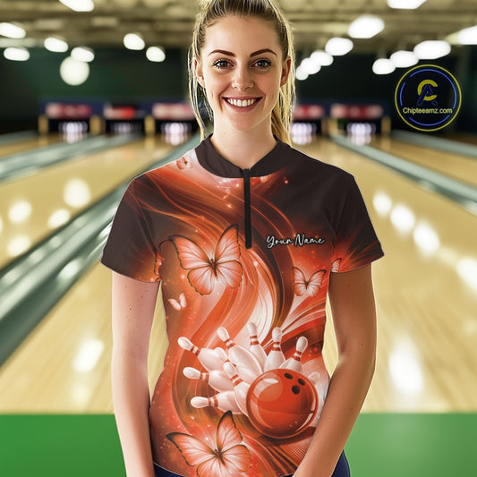 Female model wearing an orange bowling quarter-zip in a bowling lane with bowling strike graphics and butterflies.