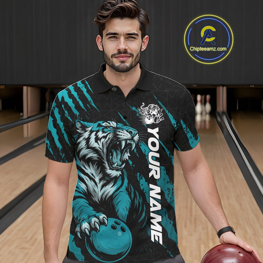 Front view of a male model at a bowling lane wearing a black and teal blue bowling polo shirt featuring a roaring tiger holding a teal blue bowling ball with matching claw-stripe graphics and a geometric background pattern.