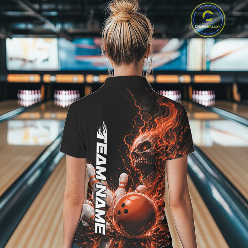 Back view of a female model in a bowling alley wearing a black bowling polo shirt featuring an orange fiery skull with lightning striking a bowling ball and pins and a custom name.

