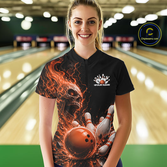 Front view of a female model in a bowling alley wearing a black bowling quarter zip shirt featuring an orange fiery skull with lightning striking a bowling ball and pins and a custom name.
