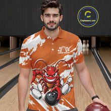 Load image into Gallery viewer, Front view of a male model in a bowling alley wearing an orange custom bowling polo shirt with a fierce yet funny crawfish bowling character and a distressed background design.