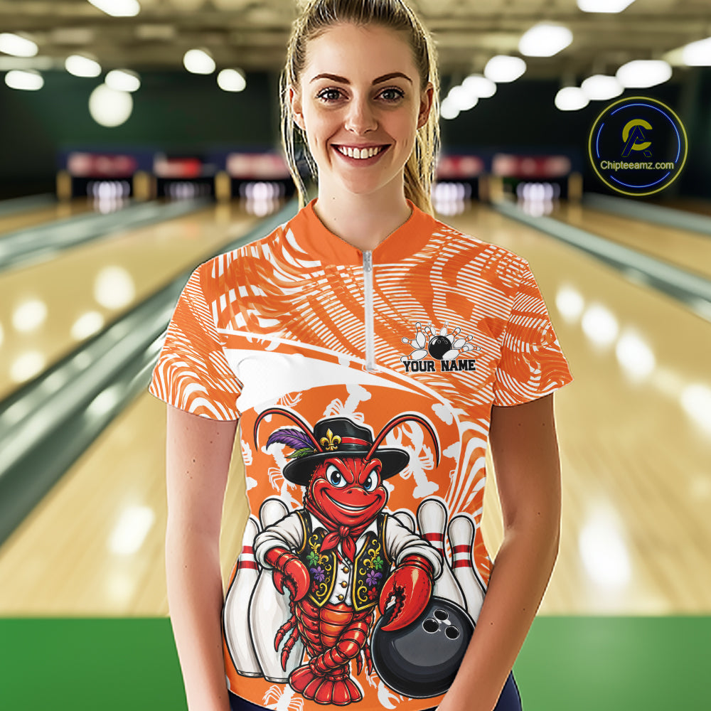 Front view of a happy female model in a bowling alley wearing an orange custom quarter-zip bowling shirt with a funny Cajun crawfish leaning on a bowling ball and a swamp-inspired texture background.