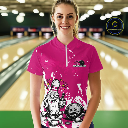 Front view female model in pink and white quarter zip bowling shirt inside bowling lane, cartoon bowling pin beer graphic with energetic styling