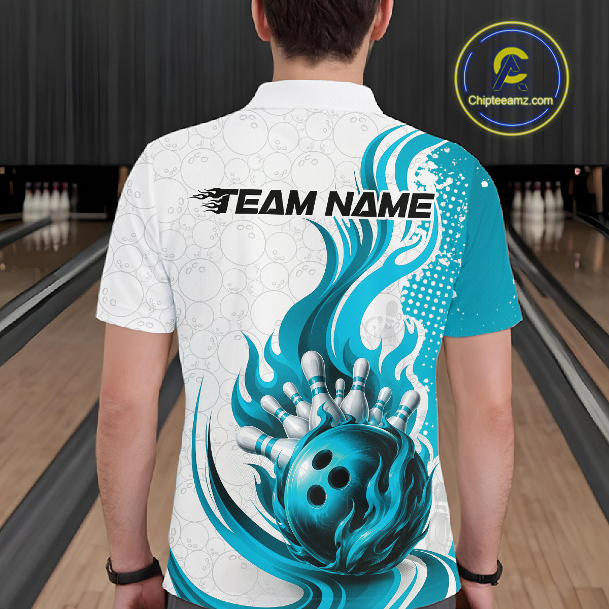 A person viewed from behind wearing a white short-sleeve bowling-themed polo shirt with a large blue and teal graphic of a bowling ball and pins, plus 'TEAM NAME' text across the upper back. Bowling lanes are visible in the background