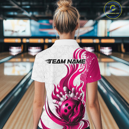 A woman viewed from behind wearing a white bowling-themed short-sleeve shirt with a bright pink and white flame-and-bowling-ball graphic on the back, standing in a bowling alley.