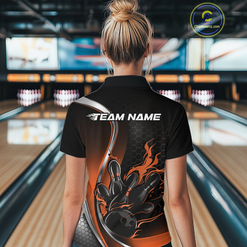 Female model back view at bowling venue wearing black and orange polo shirt showcasing flame bowling ball striking pins in bold motion artwork.