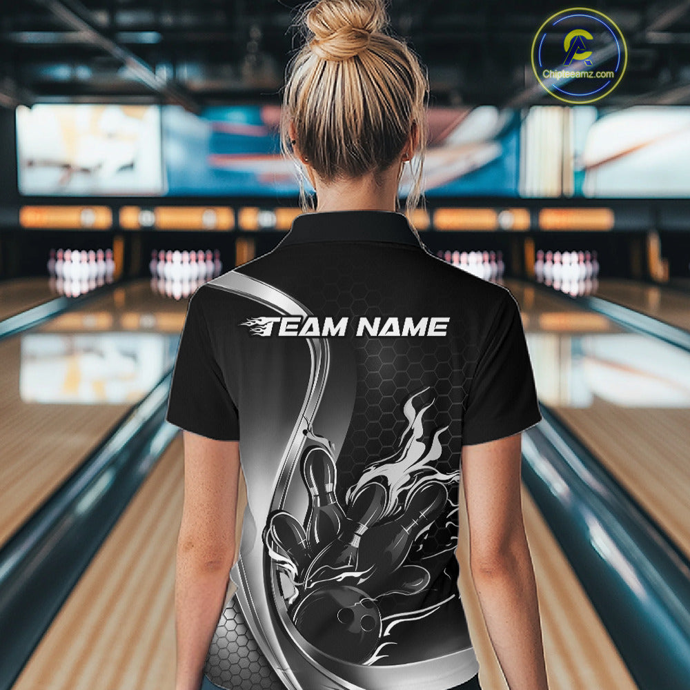 Female model back view at bowling lane wearing black and gray polo shirt showcasing flame bowling ball striking pins in clean sports design.