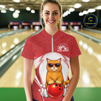 Female model wearing a white and red bowling quarter-zip shirt at a bowling lane with an orange British Shorthair cat in sunglasses beside a bowling ball.