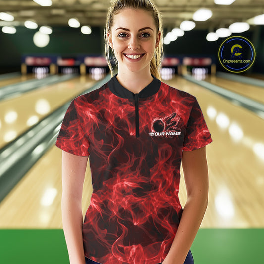 Female model in a bowling center wearing a red quarter-zip with fiery bowling ball graphics.