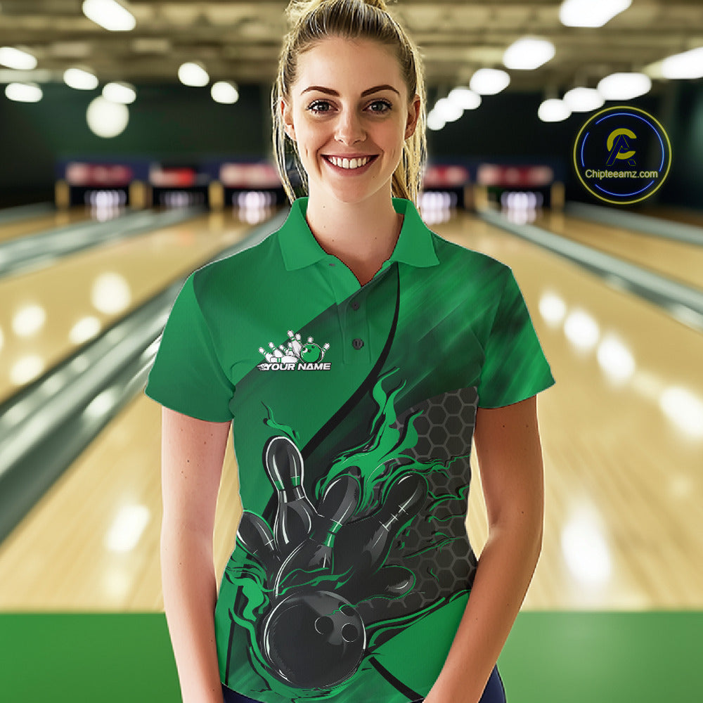 Female model at a bowling lane wearing a black and green bowling polo shirt with fiery bowling strike artwork and hexagonal graphics.