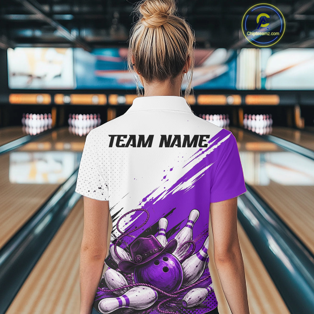 A woman viewed from behind wearing a custom bowling-themed short-sleeve polo shirt. The back of the white polo features a purple and white paint-splatter graphic with bowling pins and a purple bowling ball, and the text 'TEAM NAME' printed in black.