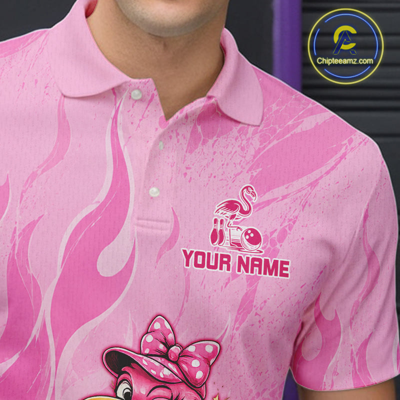 A close-up of a pink short-sleeve polo shirt worn by a model. The shirt features a flame pattern, a pink flamingo graphic with a golf ball and club, and the customizable text 'YOUR NAME'.