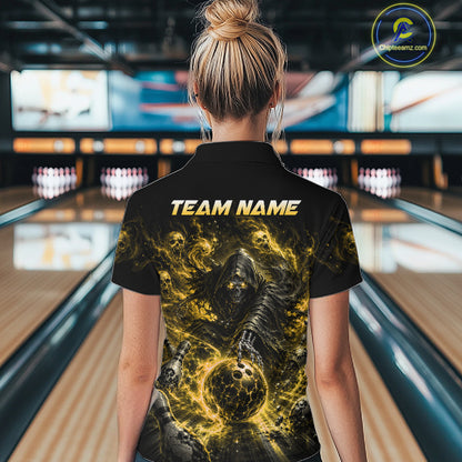 Woman wearing a black and yellow shirt with a design of a skeleton holding a bowling ball in a bowling alley.