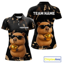 Load image into Gallery viewer, Two polo shirts with a capybara holding a bowling ball design, one with 'Your Name' and the other with 'Team Name'.