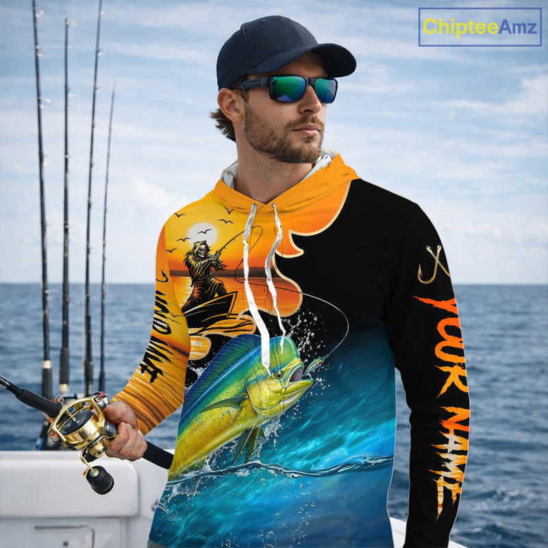 Man wearing a colorful long sleeve hooded fishing shirt with a design of a mahi mahi fish and a fish reaper, standing on a boat with fishing rods in the background.