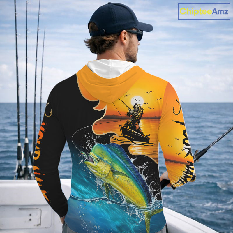 Person wearing a saltwater long sleeve hooded fishing shirt with a sunset and fish reaper design, standing on a boat.