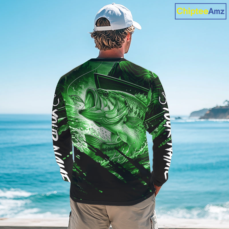 Person wearing a green and black bass fishing shirt with a fish design, standing by the ocean.