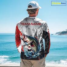 Load image into Gallery viewer, A man wearing a bass fishing shirt long sleeve with a large fish graphic and 'TEAM NAME' text, standing by the ocean.