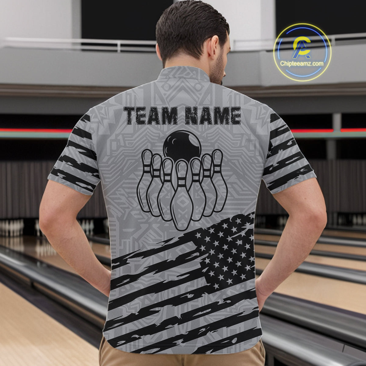 Back view of man wearing a grey American flag bowling quarter zip shirt at a bowling alley.