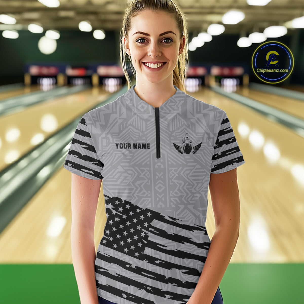 Front view of woman wearing a grey American flag bowling polo shirt inside a bowling alley.