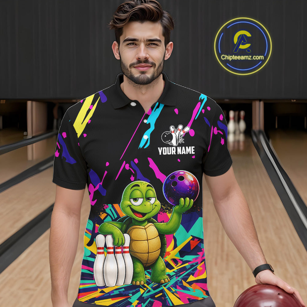Man wearing a colorful bowling-themed shirt with a turtle graphic in a bowling alley.