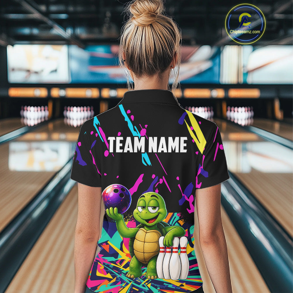Person wearing a colorful bowling-themed shirt with a turtle design in a bowling alley.
