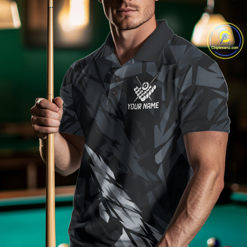 Man wearing a black and grey billiard jersey beside a pool table front view.